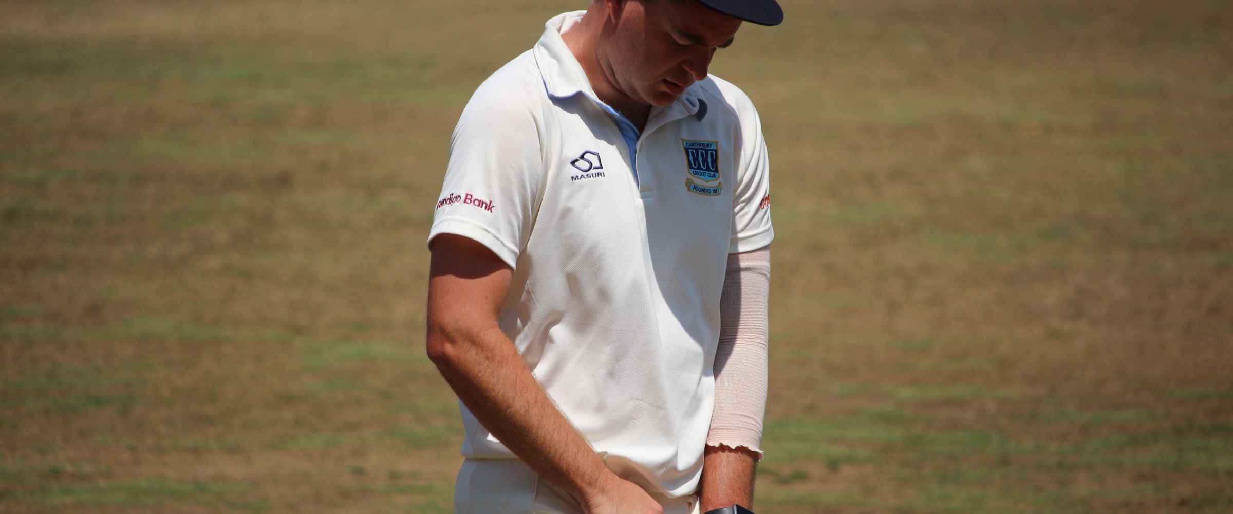 A Canterbury player on the outfield at Canterbury Sports Ground in the club cap and playing shirt, the club crest on both and the Bendigo Bank sleeve logo visible