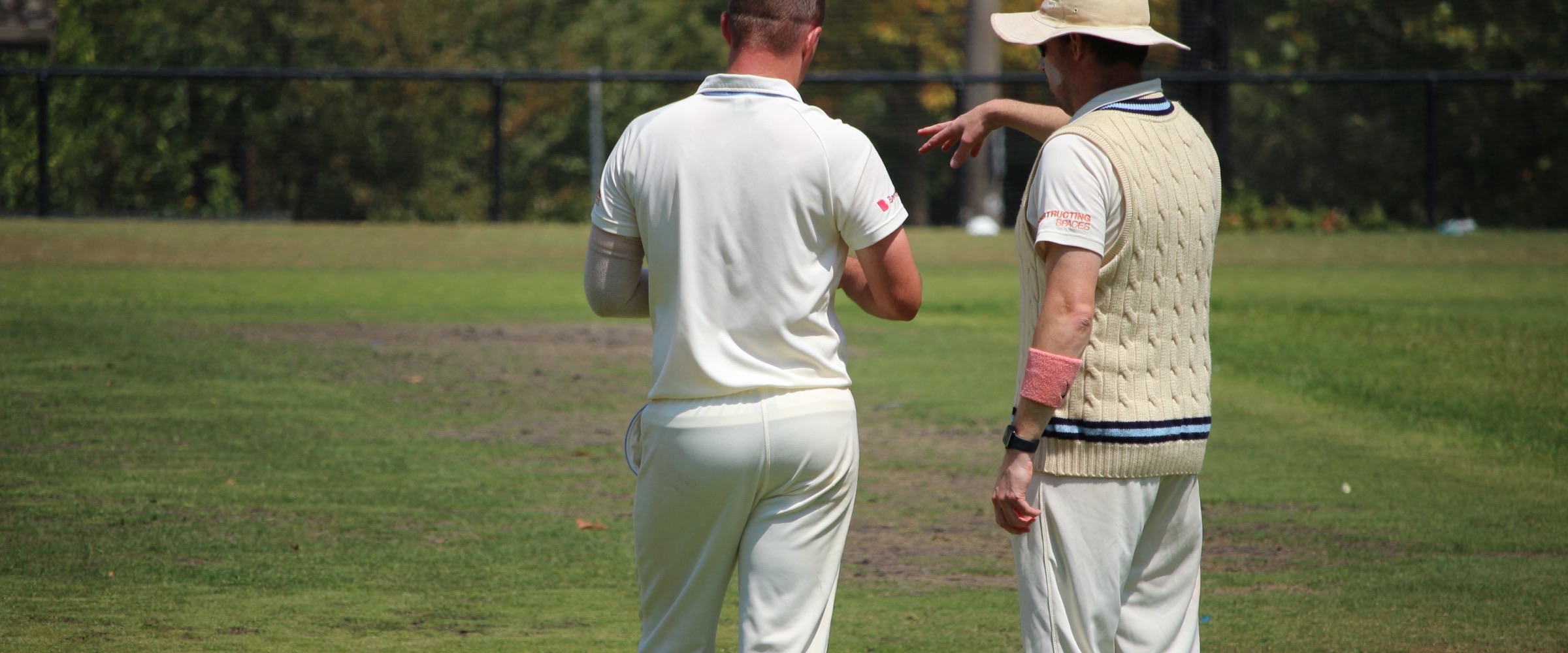 Two Canterbury players setting the field between overs at Canterbury Sports Ground, one pointing to a position