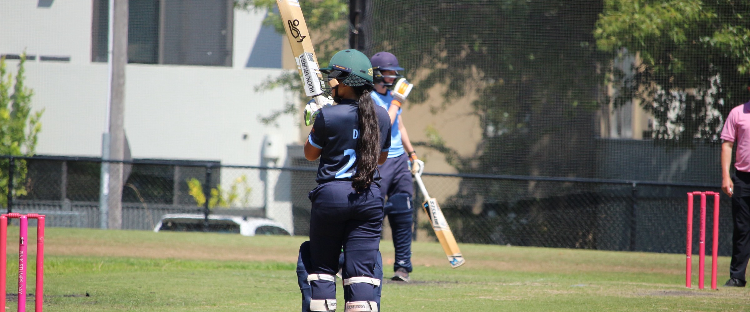 Two Canterbury batters meet mid-pitch between deliveries on Pink Stumps Day, the pink stumps set at both ends