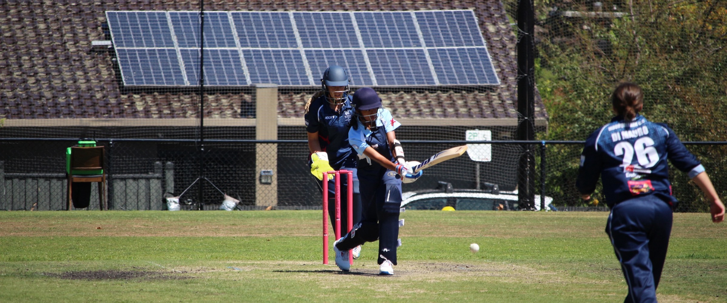 A Canterbury batter drives a white ball through the off side on Pink Stumps Day, the wicketkeeper behind the pink stumps and a fielder closing in